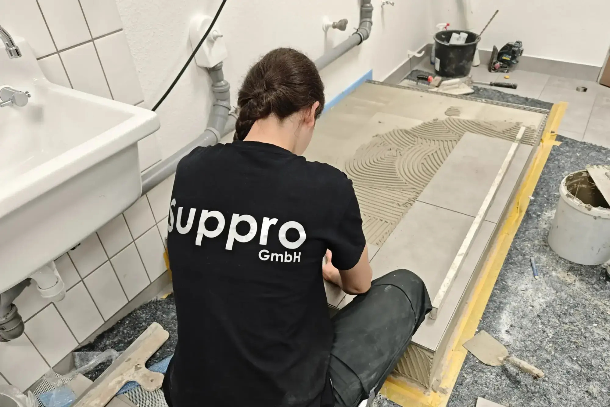 Fliesenleger der Suppro GmbH verlegt Bodenfliesen bei einer Badsanierung im Rhein-Main-Gebiet